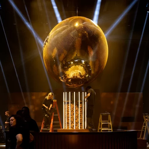 Gold mirror football centerpiece on stage with dramatic beam lighting